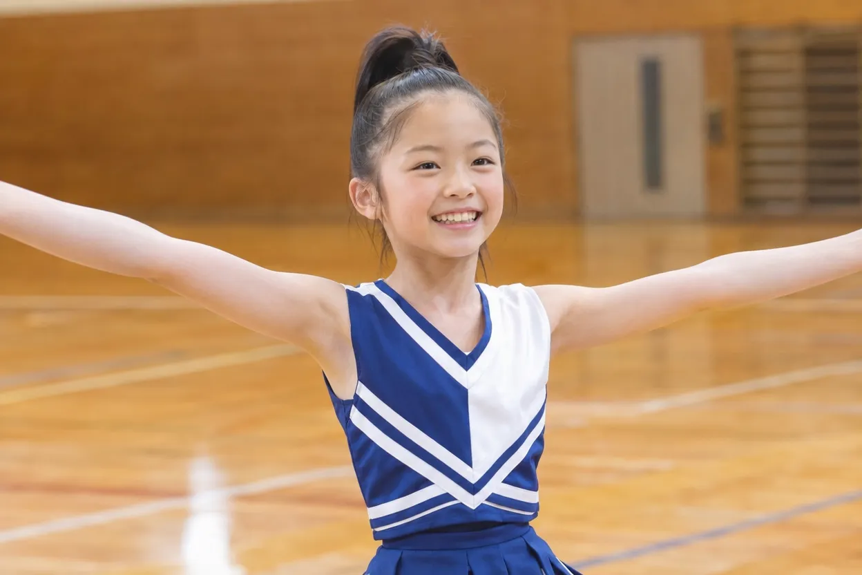おでこを出したポニーテールで、のびのびと腕を広げて踊るチアの女の子