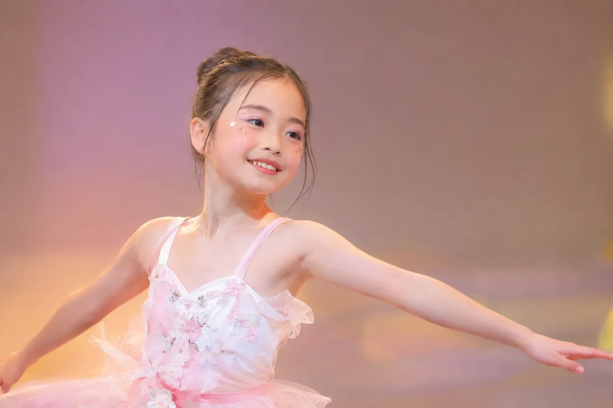 発表会のステージで、自然な笑顔で踊るメイクをした女の子